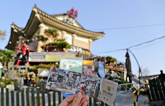 추억의 달동네 배경으로 입장티켓을 들고있는 손 사진