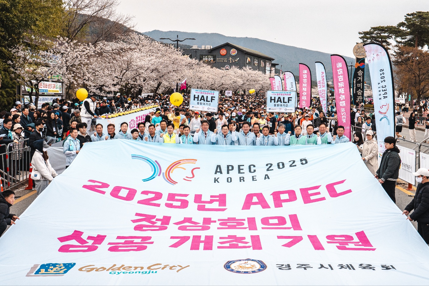 지난 5일 경주 보문관광단지에서 열린 제32회 경주벚꽃마라톤대회에서 주낙영 경주시장을 비롯한 내빈과 참가자들이 ‘2025년 APEC 정상회의 성공개최 기원’ 문구가 적힌 대형 현수막을 펼치고 있다.
