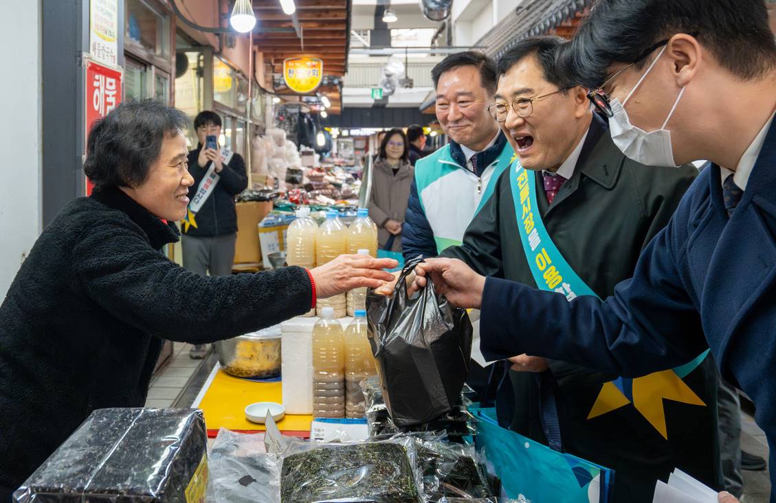 주낙영 경주시장이 전통시장 상인을 만나 물건을 구입하며 인사를 나누고 있다. 경주시는 2025 APEC 정상회의를 앞두고 전통시장 환경 개선 사업을 추진 중이다.