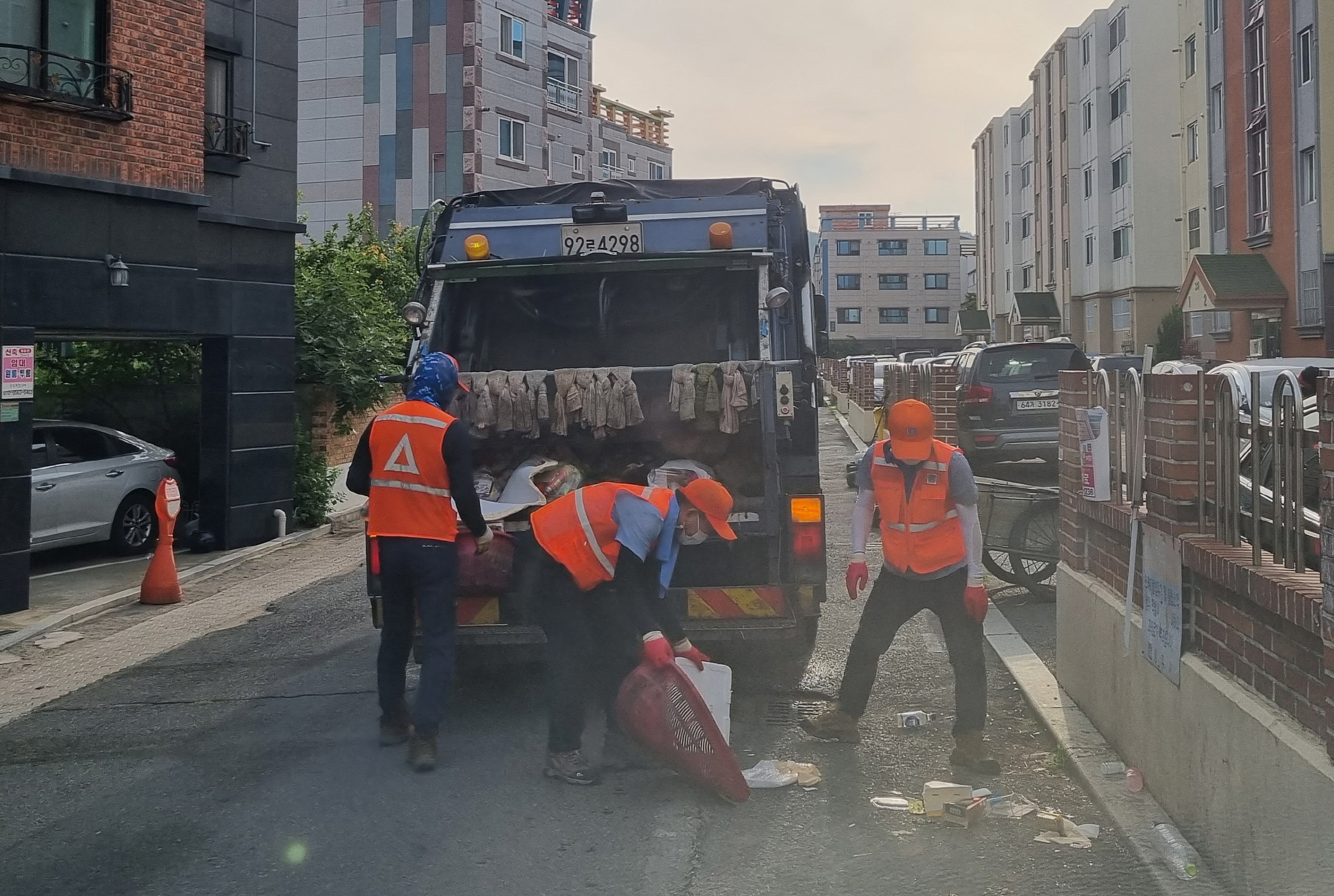 환경미화원과 자원순환과 직원이 이른 아침 쓰레기를 수거해 청소차에 투입하고 있다
