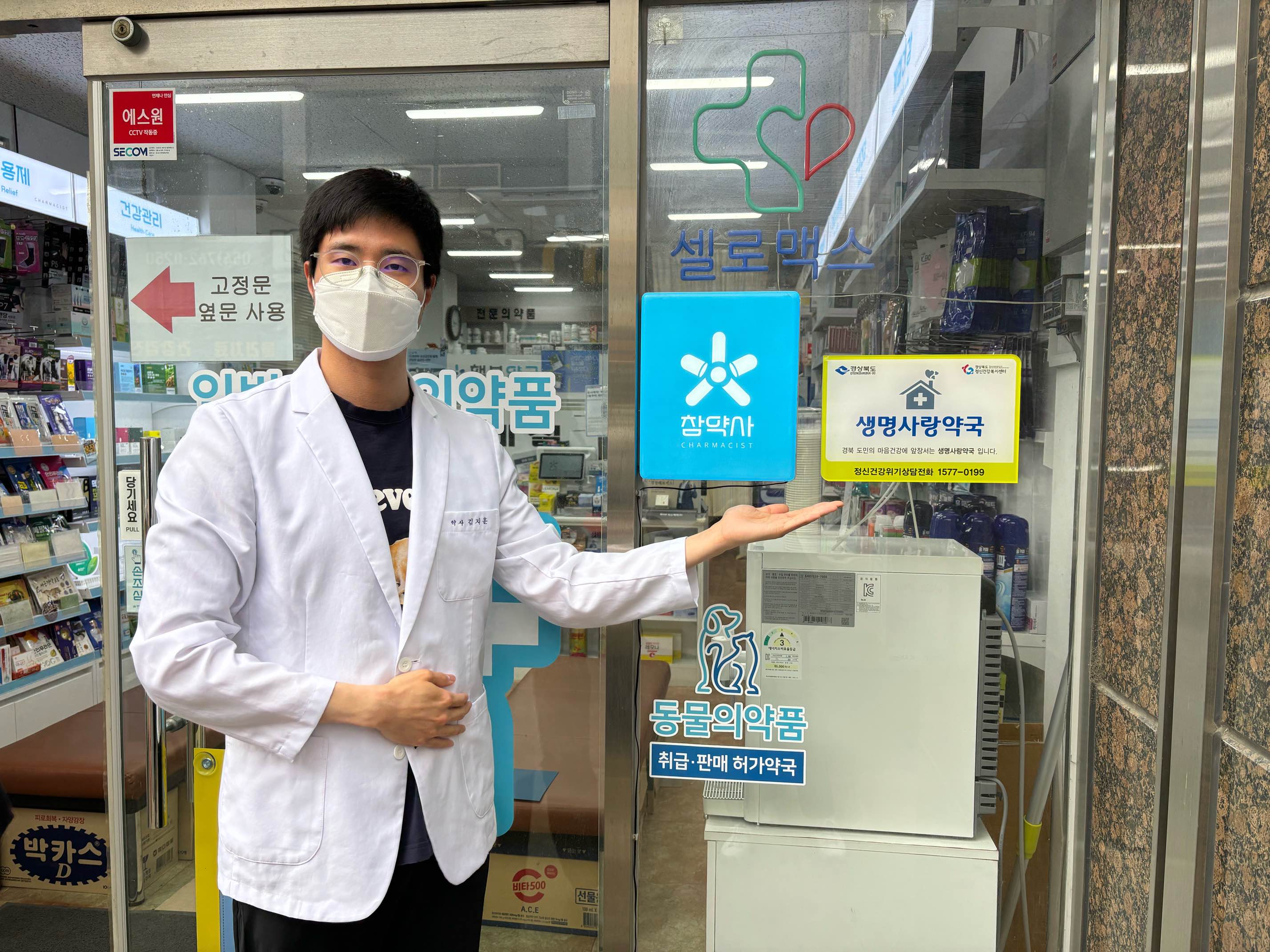 경주시정신건강복지센터와의 ‘생명사랑 약국’ 업무협약을 맺은 후, 경주시 안강읍 참약사행복약국 김지훈 약사가 약국 입구에 부착된 명패를 소개하고 있다.