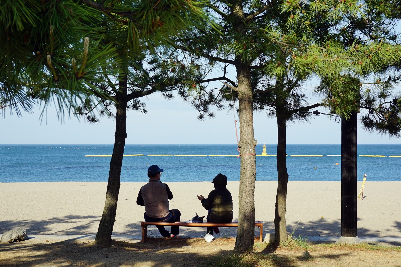 나정고운모래해변 벤치에서 대화를 나누는 관광객의 모습